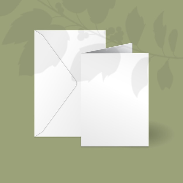 Carta verticale bianca e modello di busta con ramo di bacche di agrifoglio con foglie sovrapposte ombra.