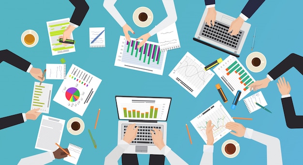 Concetto di lavoro di squadra. Vista superiore del brainstorming, riunione d'affari della scrivania. Mani con l'illustrazione dei computer portatili e dei documenti