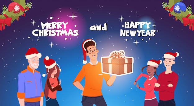 Gente felice che indossa Santa Hats Man Holding Present Box Natale e Capodanno feste celebrazione