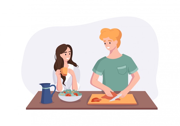 La giovane coppia sta parlando mentre cucinava la colazione a tavola in cucina. Donna che beve caffè e parlando con suo marito. Uomo che prepara i pasti a casa.