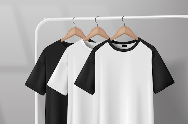 Magliette bianche e nere appese su un rack per i vestiti in uno studio su un appendiabiti in legno