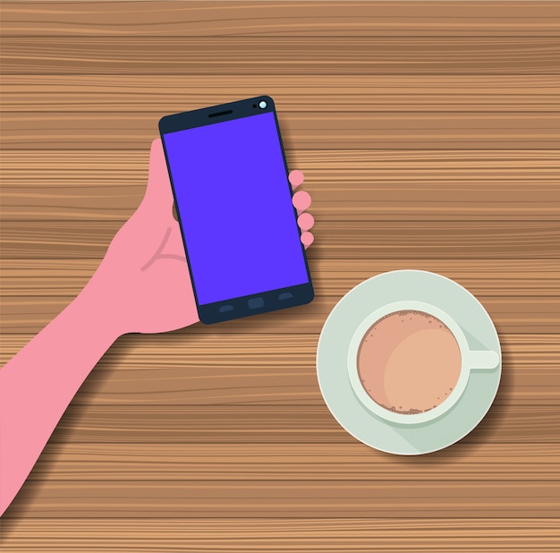 mano utilizzando smartphone con tazza di caffè in tavola