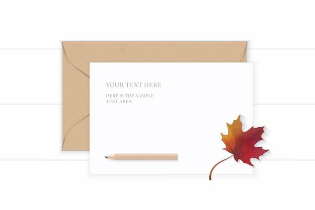 Piatto laici vista dall'alto elegante composizione bianca lettera busta in carta kraft matita e foglia di acero rosso autunno su sfondo di legno.