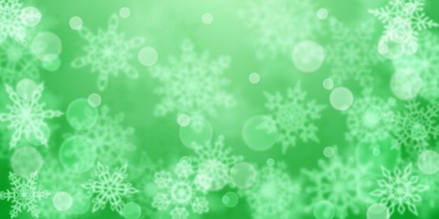 Sfondo natalizio di fiocchi di neve sfocati in colori verdi