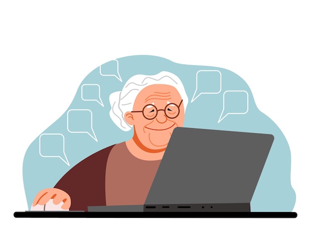Una donna anziana lavora a casa al computer. La nonnina carina è seduta alla sua scrivania e lavora.