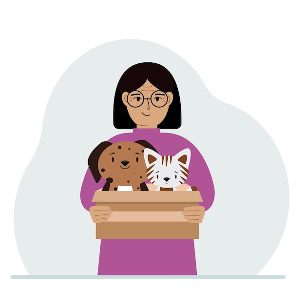 Una donna tiene una scatola di cartone con un gatto e un cane Il concetto di aiuto di salvataggio e cura degli animali domestici
