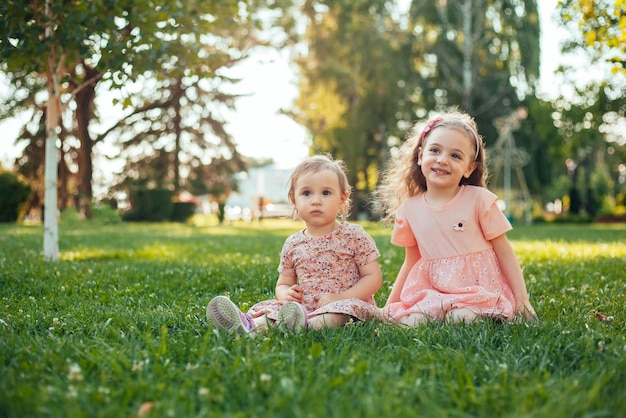 1 en 3 jaar oude zus zitten op het groene gras in het park