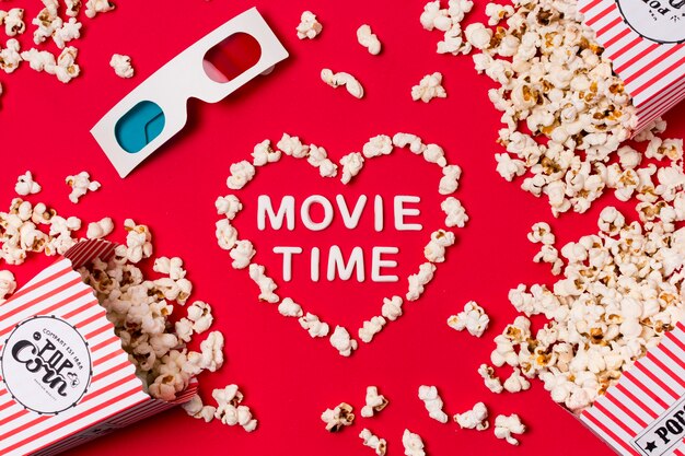 3D bril; popcorn gemorst uit vak met film tijd tekst in hart vorm op rode achtergrond