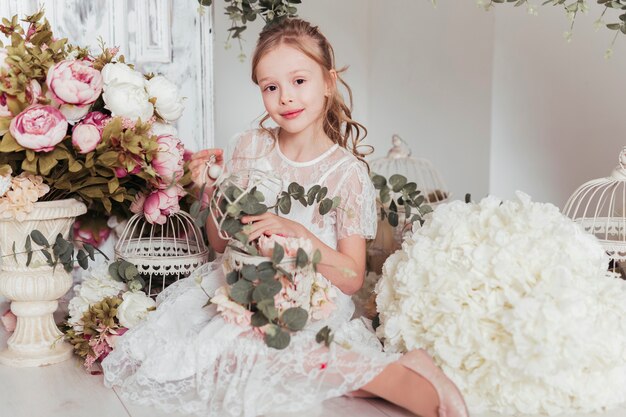 Aanbiddelijk meisje dat door bloemen wordt omringd