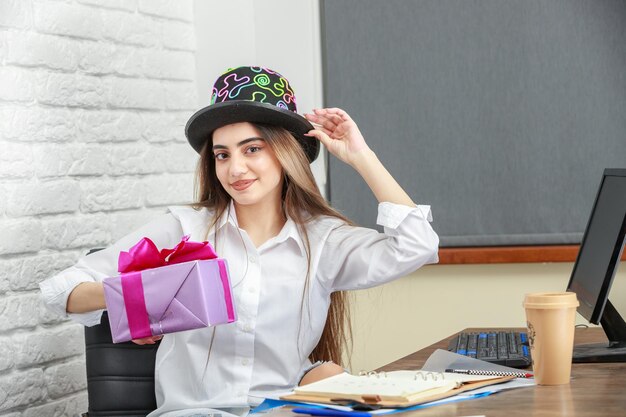 Aanbiddelijk meisje dat een hoed draagt en de huidige doos vasthoudt Foto van hoge kwaliteit