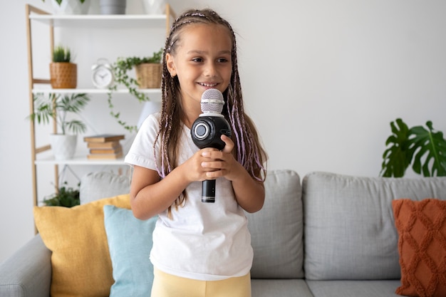 Gratis foto aanbiddelijk meisje dat thuis bij een microfoon zingt