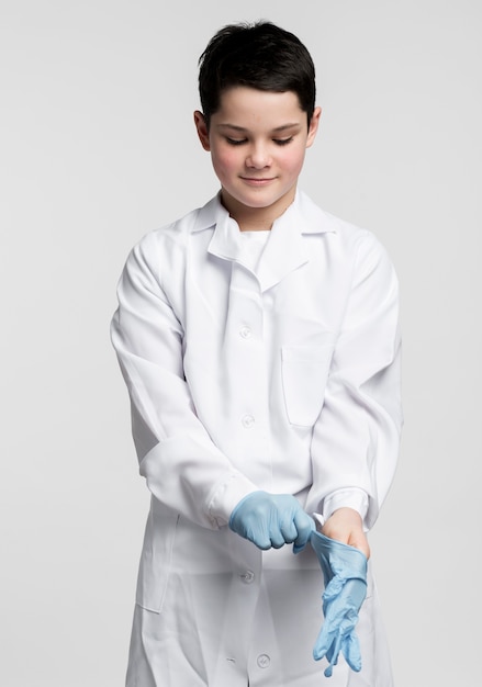 Gratis foto aanbiddelijke jonge jongen die chirurgische handschoenen voorbereidt