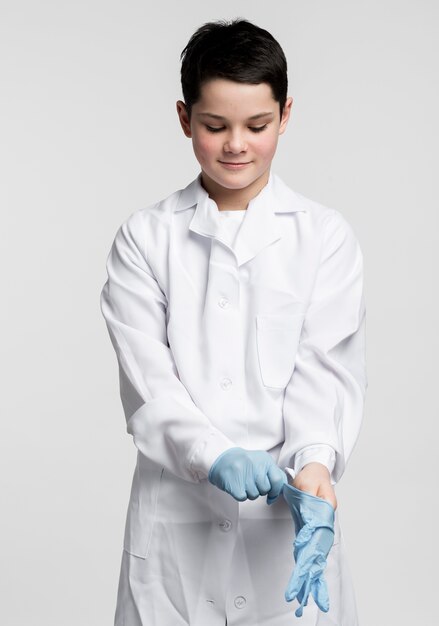 Aanbiddelijke jonge jongen die chirurgische handschoenen voorbereidt