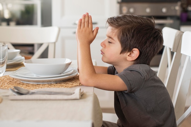Aanbiddelijke jonge jongen die thuis bidt