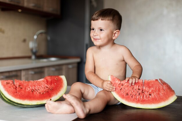 Aanbiddelijke jonge jongen met plakken van watermeloen