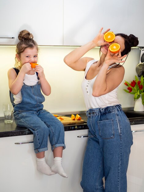 Gratis foto aanbiddelijke jonge meisje en moeder samen in keuken