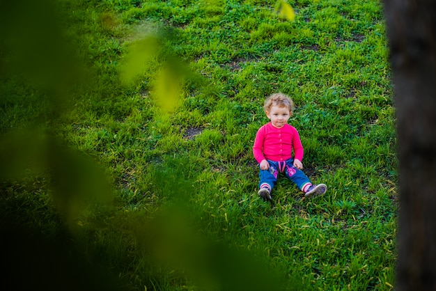 Aanbiddelijke kleine jongen die op het gazon zit