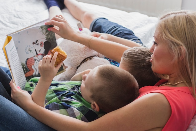 Aanbiddelijke scène van de moeder die een boek leest met haar kinderen