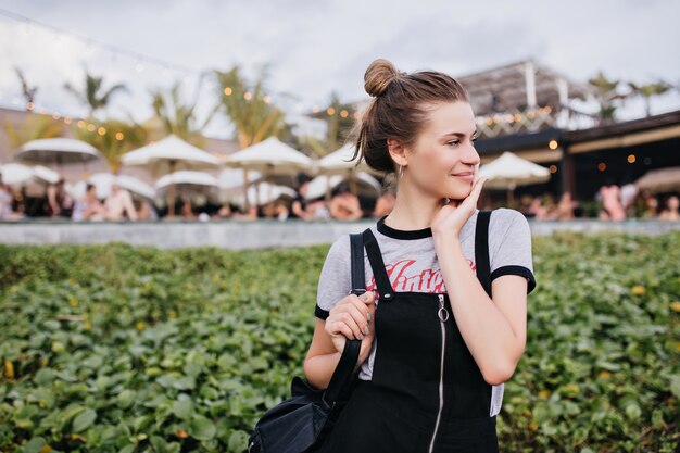 Aangenaam Kaukasisch meisje poseren met een verlegen glimlach op de natuur. Foto van schattig vrouwelijk model met schattig kapsel rusten in resort stad.