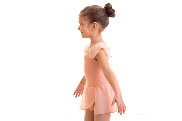 Aangenaam klein meisje in roze jurk dansen op witte achtergrond in studio