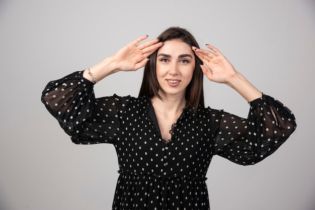 Aangenaam uitziende jonge brunette vrouw permanent en poseren.