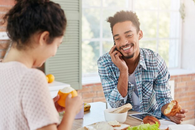 Aangenaam uitziende stijlvolle bebaarde man spreekt via slimme telefoon