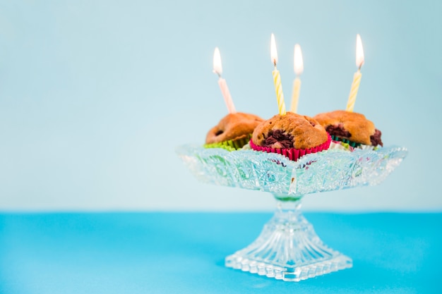 Aangestoken kaarsen over de cupcake op blauwe achtergrond