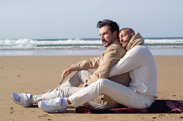 Aanhankelijk man knuffelen vriendje op het strand. Kalme kale homo knuffelende vriend op zee. LGBT-concept