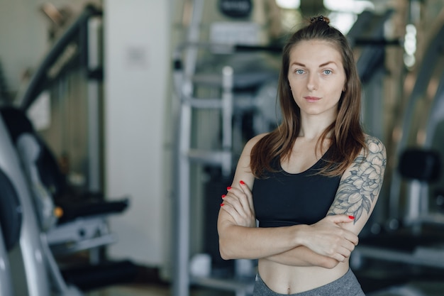 Aantrekkelijk atletisch meisje staat op de muur van simulatoren in de sportschool. gezonde levensstijl.