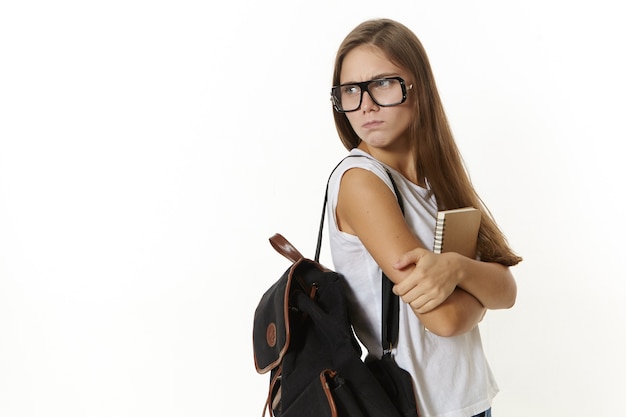 Aantrekkelijk gefrustreerd universiteitsmeisje die rugzak en leerboek draagt, boos is over mislukte examens, veel huiswerk