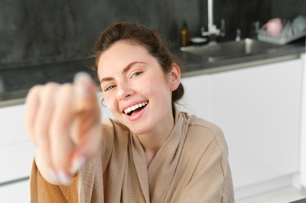 Gratis foto aantrekkelijk jong vrolijk meisje dat in de keuken bakt en deeg maakt met receptenboek met ideeën