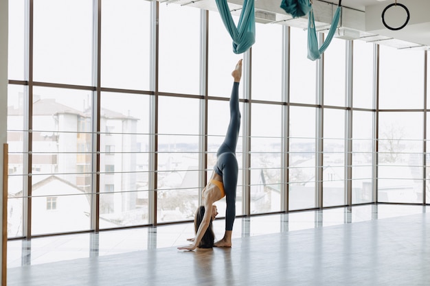 Aantrekkelijk meisje doet fitness oefeningen met yoga op de vloer tegen het oppervlak van panoramische ramen