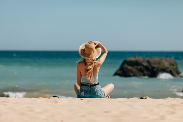 Aantrekkelijk meisje in zonnebril en hoed ligt op warm zand