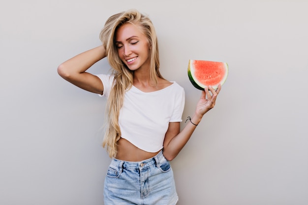 Aantrekkelijk wit vrouwelijk model in de watermeloen van de tanktopholding.