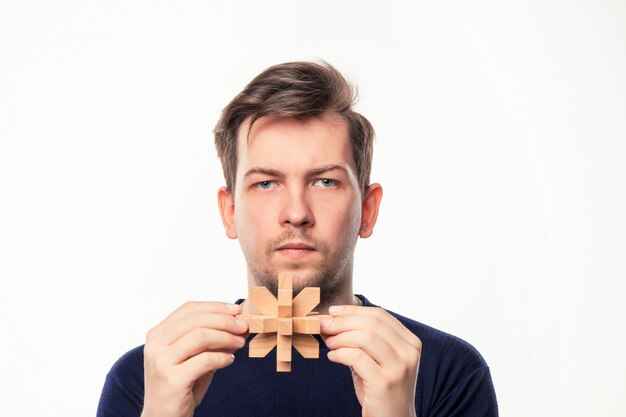 Aantrekkelijke 25-jarige zakenman op zoek verward met houten puzzel.