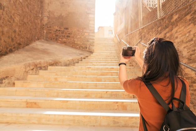 Aantrekkelijke Aziatische vrouwelijke reiziger toerisme hand gebruik camera sightseeing oude stenen trap gang in Cartagena, Spanje met geluk en vrolijk reisreis concept