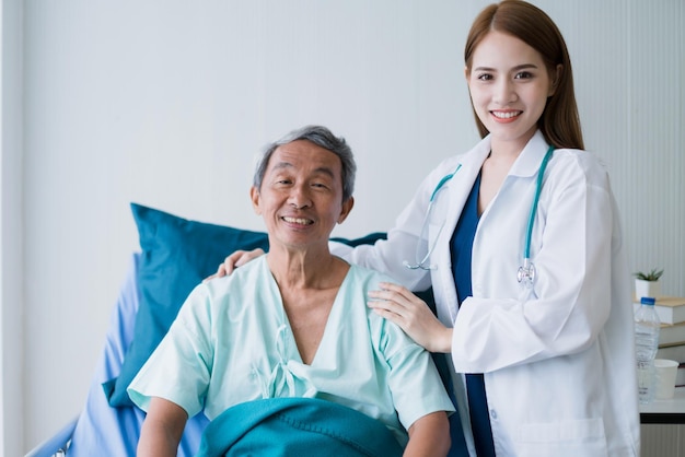 Aantrekkelijke aziatische vrouwenverpleegster en arts werken met glimlach en frisheid samen om de zieke oude senior patiënt in het ziekenhuis te verzorgen