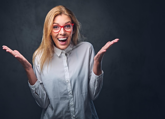 Aantrekkelijke blonde zakenvrouw in een wit overhemd over grijze achtergrond.