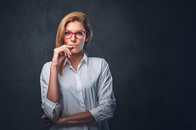 Aantrekkelijke blonde zakenvrouw in een wit overhemd over grijze achtergrond.