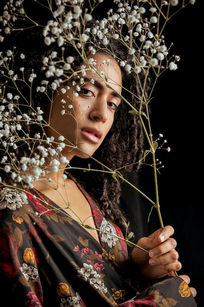 Aantrekkelijke etnische charmante vrouw met bloemtwijgen in duisternis