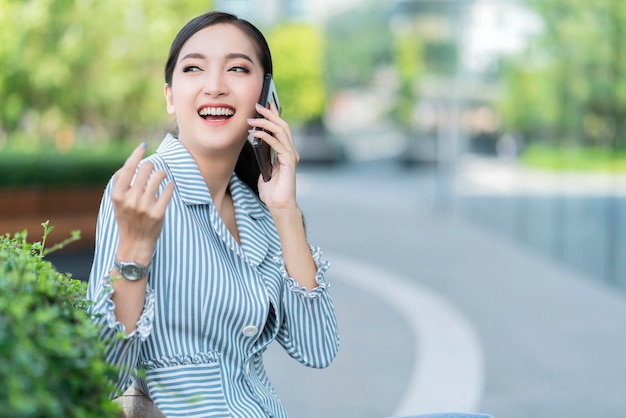Aantrekkelijke glimlach vrolijke Aziatische vrouwelijke zakenvrouw smartphone communicatietechnologie gebouw tuin buiten locatie gratis copysapce