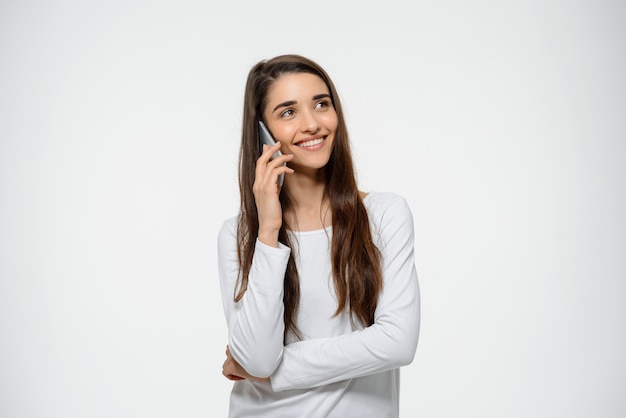 Aantrekkelijke glimlachende vrouw die op mobiele telefoon spreekt