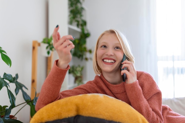 Gratis foto aantrekkelijke glimlachende vrouw die smartphone gebruikt terwijl ze thuis op de bank zit communicatie en gezelligheid concept