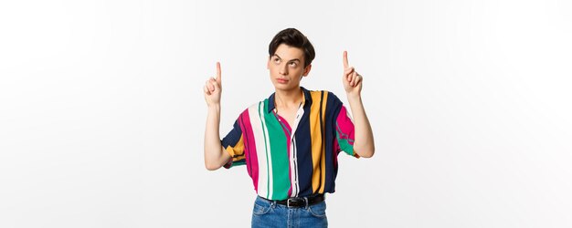 Aantrekkelijke homoseksuele man die attent kijkt met de vingers omhoog naar het logo dat op een witte achtergrond staat