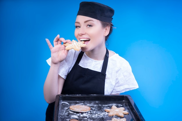 Gratis foto aantrekkelijke huisvrouw die vers gebakken peperkoekkoekje proeft