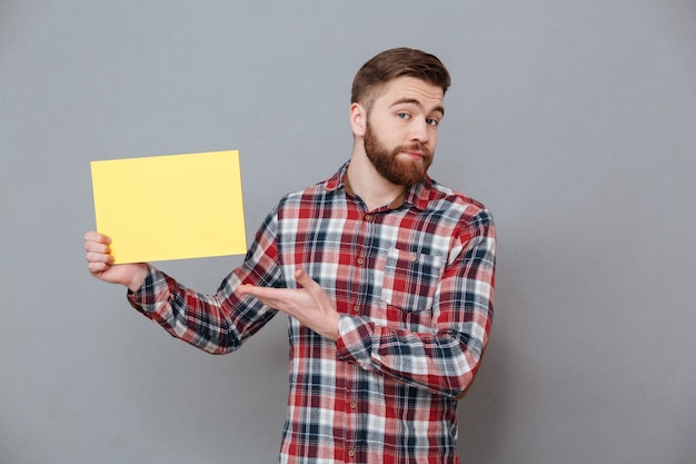 Gratis foto aantrekkelijke jonge bebaarde man met blanco papier