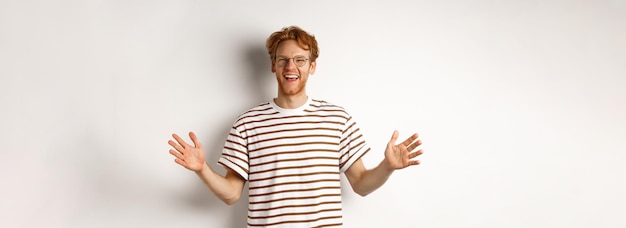 Gratis foto aantrekkelijke jonge man met rood haar en een bril met een grote lengte van een groot object glimlachend satis