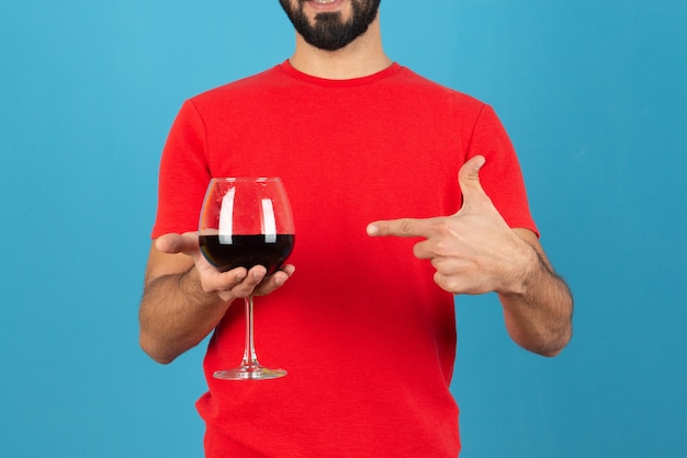 Aantrekkelijke jonge man wijzend op een glas rode wijn.