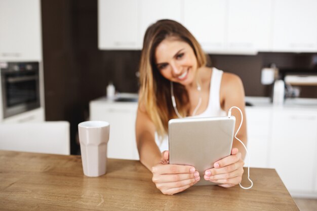 Aantrekkelijke jonge meisjeszitting bij dinerlijst en het maken van selfie met tablet