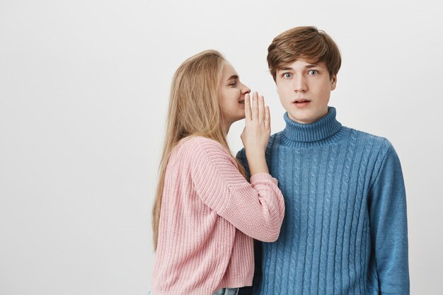 Aantrekkelijke jonge mooie vrouw die geheimen deelt of roddels fluistert in haar vriendje